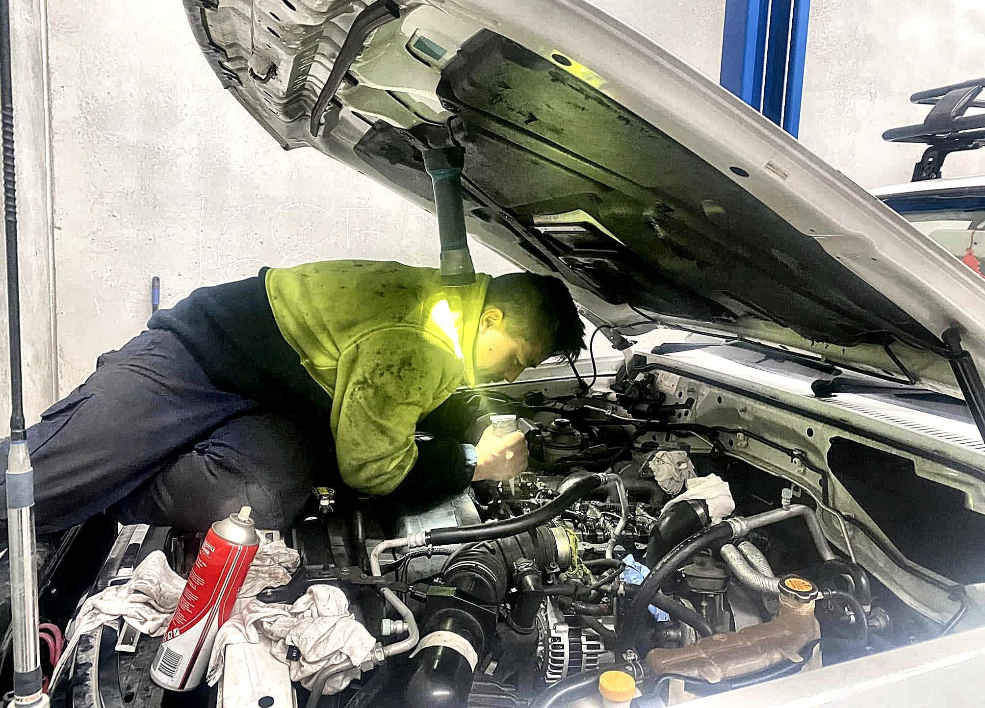 A Gurkha Automotive mechanic working under the hood of a vehicle in the Sunshine North workshop